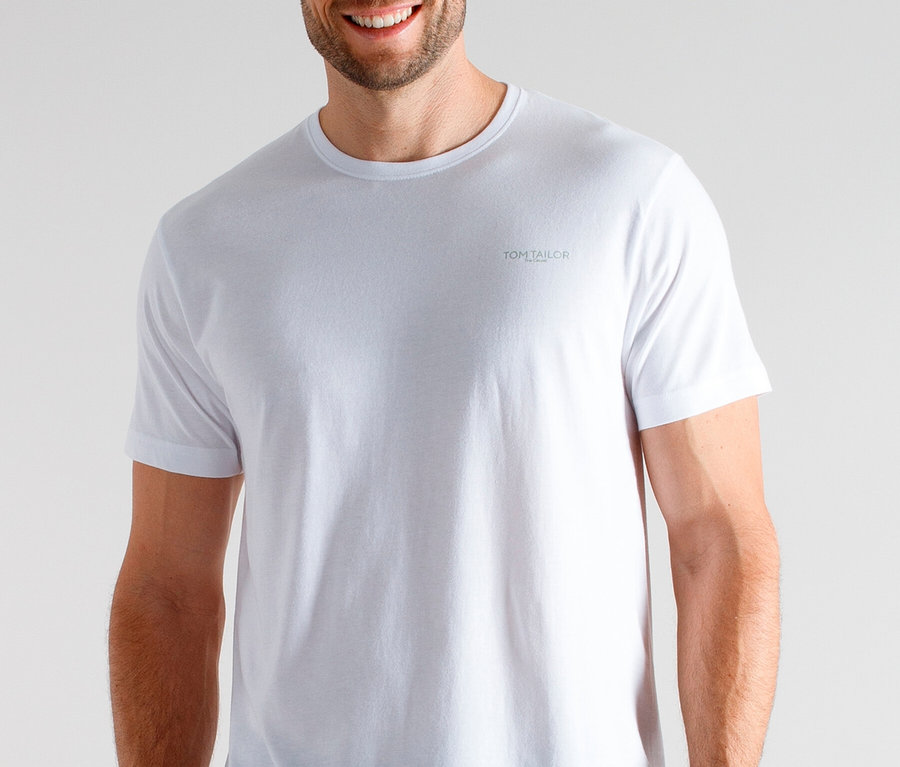 Ein lächelnder Mann trägt ein weißes T-Shirt und eine karierte Schlafanzughose.