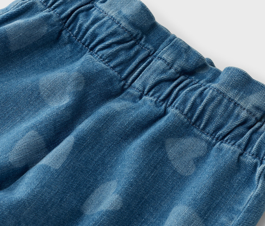 Detailaufnahme von blauen Jeans mit elastischem Bund und dezentem Herzmuster.