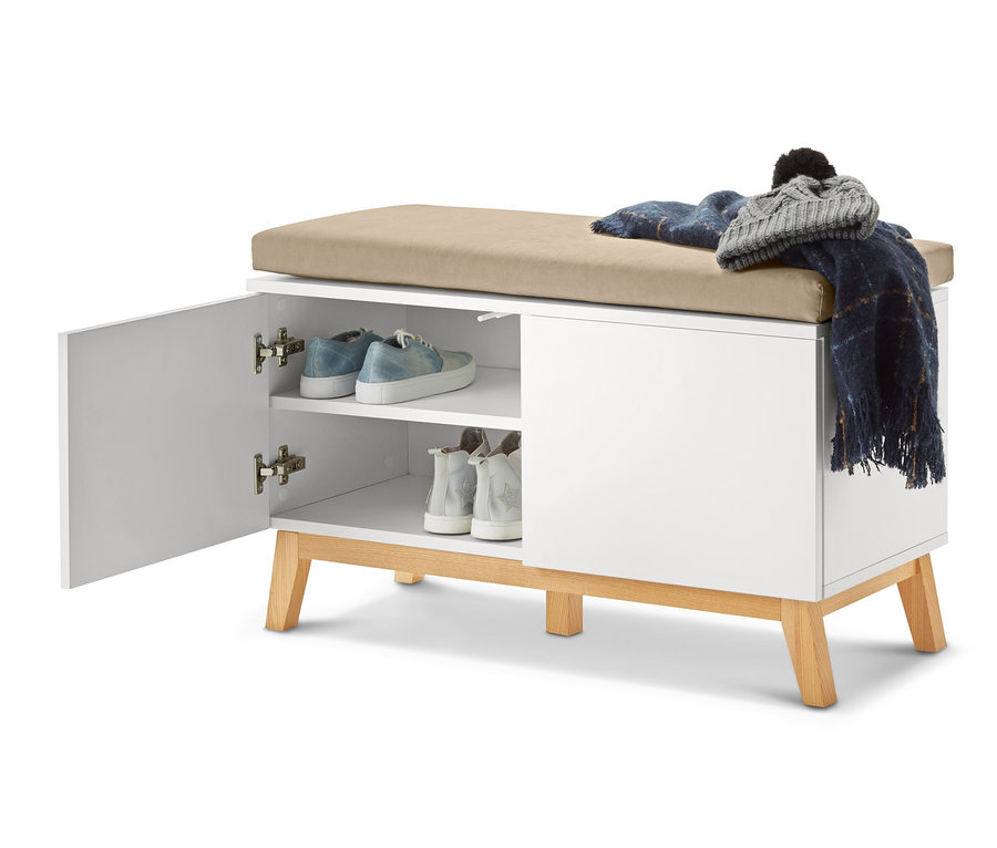Geöffnete, weiße Sitzbank mit Stauraumfächern, auf der Schuhe, eine Decke und eine Mütze liegen.