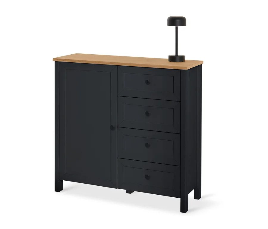 Schwarze Kommode »Clara« mit Schubladen und Tür und einer Holzplatte, auf der eine schwarze Lampe steht.