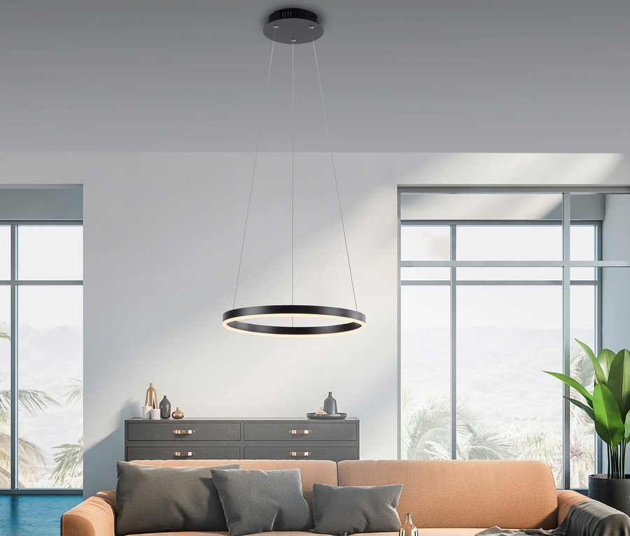 Wohnzimmer mit Sofa und schwarzer, runder JUST LIGHT LED-Pendelleuchte »Ritus«, die über einem Couchtisch hängt.