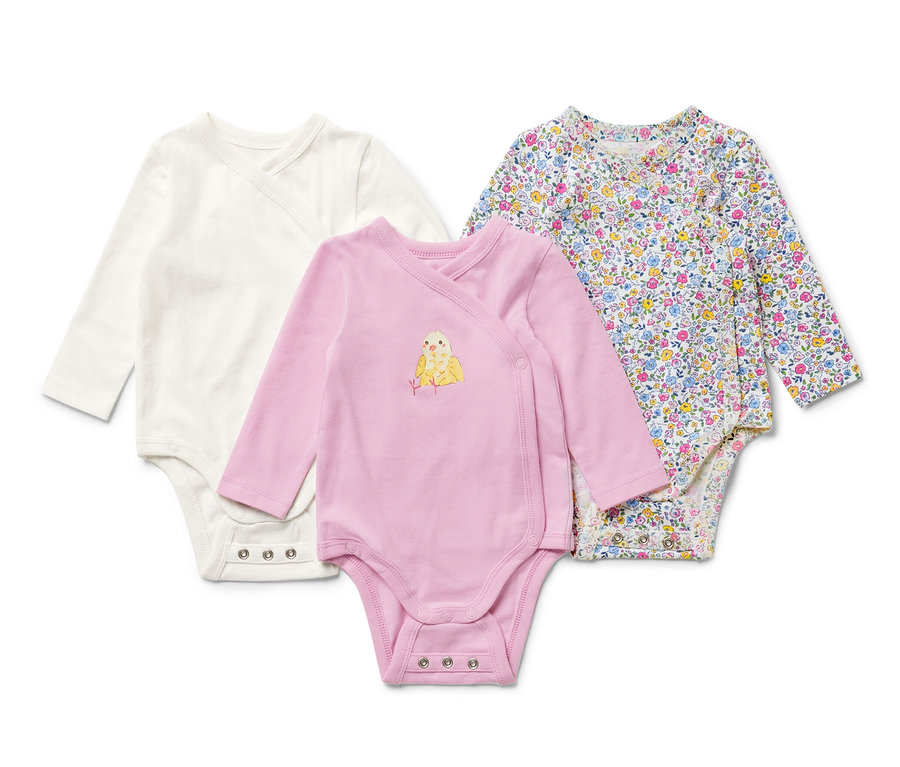 Drei Baby-Bodys mit Mitwachsfunktion, einer weiß, einer rosa mit Küken-Motiv, einer mit Blumenmuster.