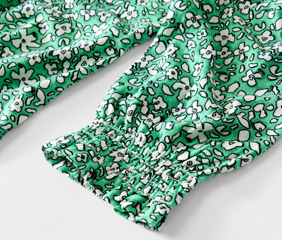 Detailansicht eines grünen, bedruckten Blusenshirts.