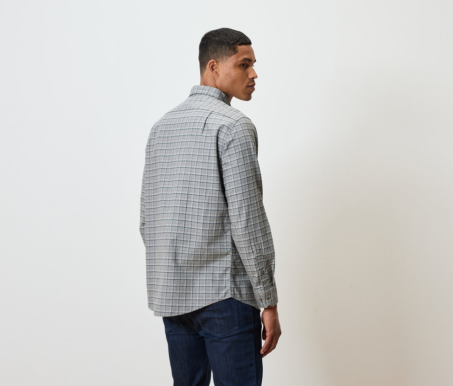 Ein Mann in einem karierten Hemd und dunklen Jeans steht mit dem Rücken zum Betrachter.
