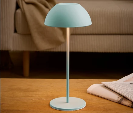 Türkise Lampe steht auf einem Tisch neben einer Zeitung.