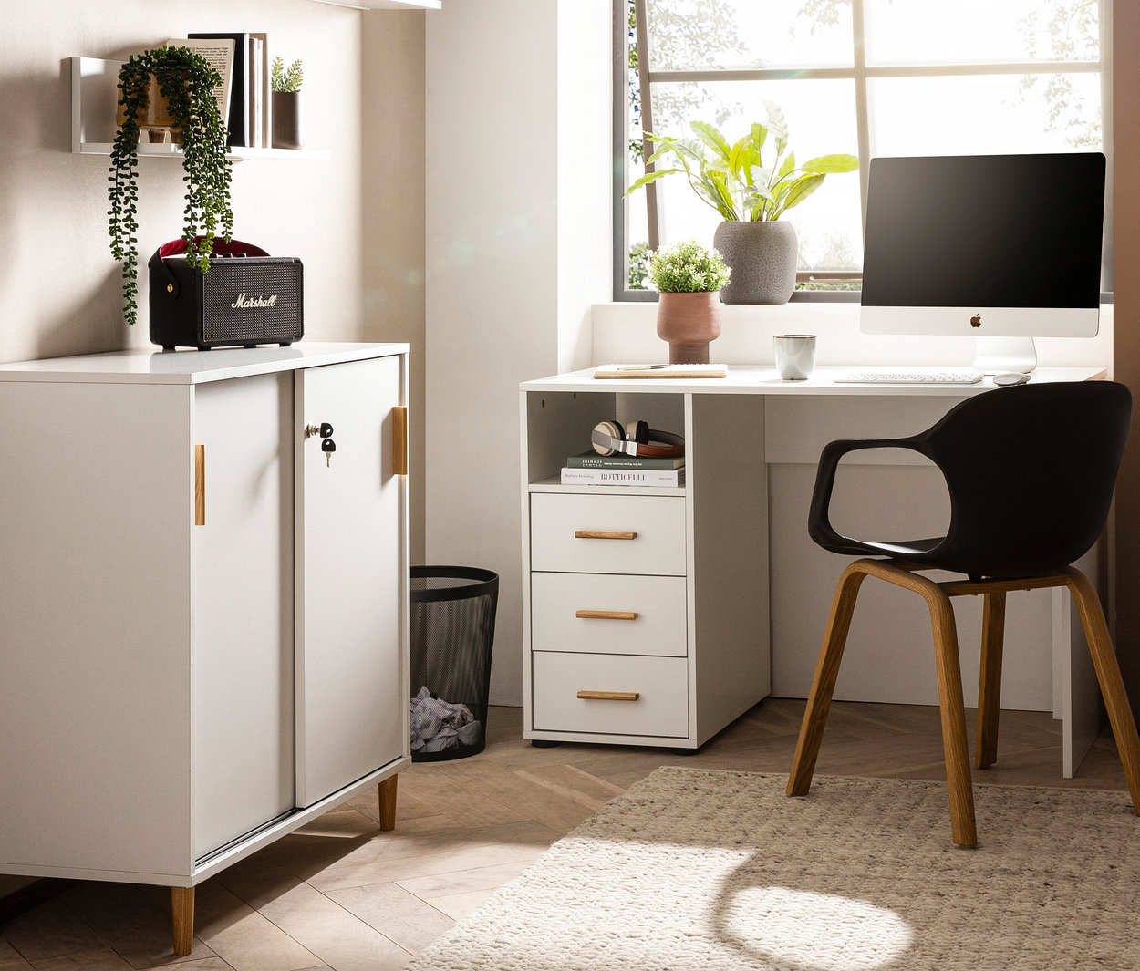 Einrichtung mit einem weißen Schreibtisch »Torge« und einem schwarzen Stuhl vor einem Fenster.