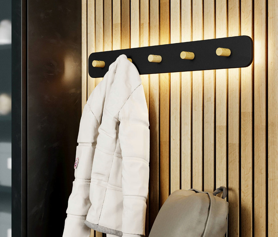 An einer Holzwand hängt eine schwarze Garderobe mit einer weißen Jacke und einem grauen Rucksack.