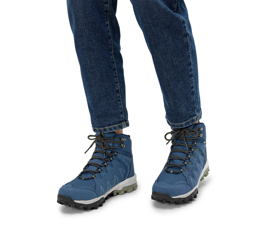 Person trägt blaue Wanderschuhe und Jeans.