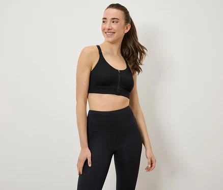 Frau trägt einen schwarzen Sport-BH und Leggings.