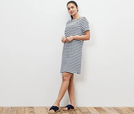 Frau steht an der Wand in einem gestreiften Jerseykleid.