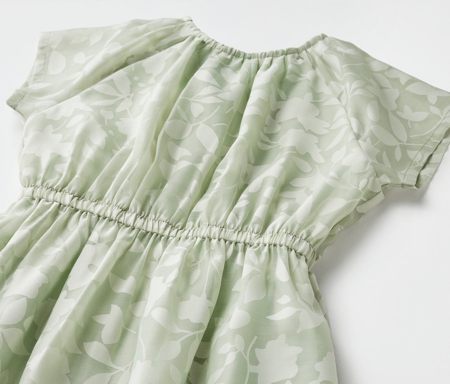 Nahaufnahme eines Kinder-Kleids mit kurzen Ärmeln und Blumenmuster.