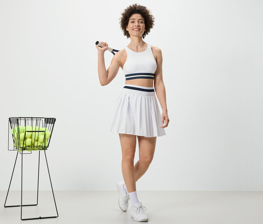 Frau hält Tennisschläger und trägt Sportrock.