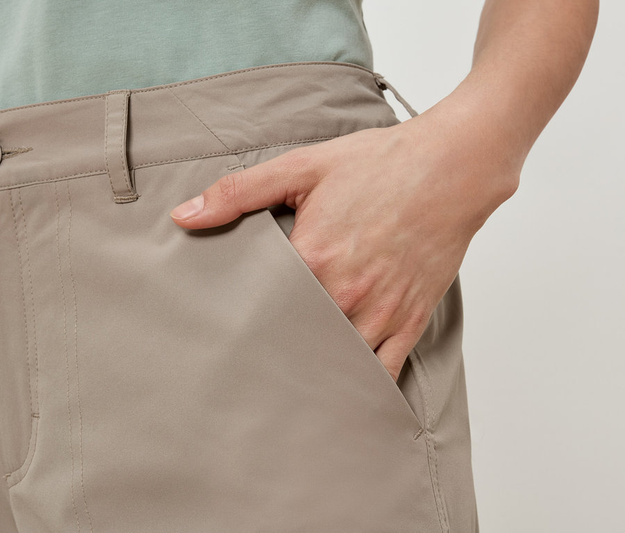 Eine Person mit der Hand in der Tasche einer beigen Hose.