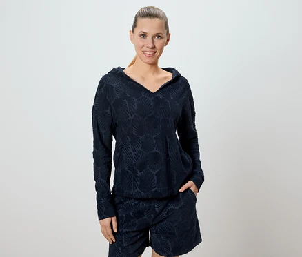 Frau trägt ein marineblaues Hoodie- und Shorts-Set mit einem Allover-Muschelmuster.