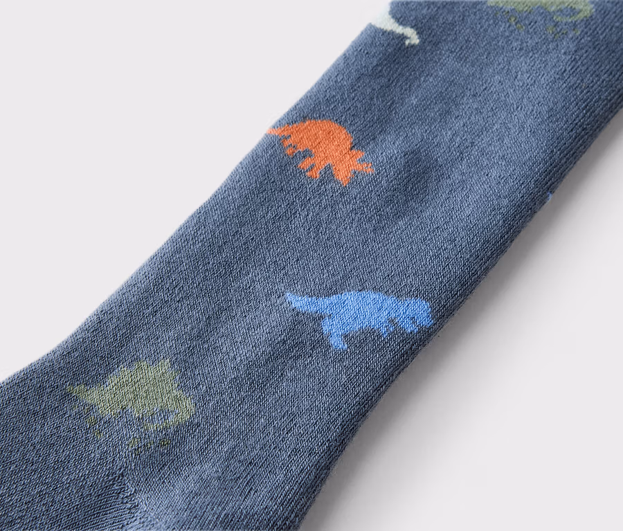 Nahaufnahme einer blauen Socke mit orangefarbenen, grünen und blauen Dinosauriern.
