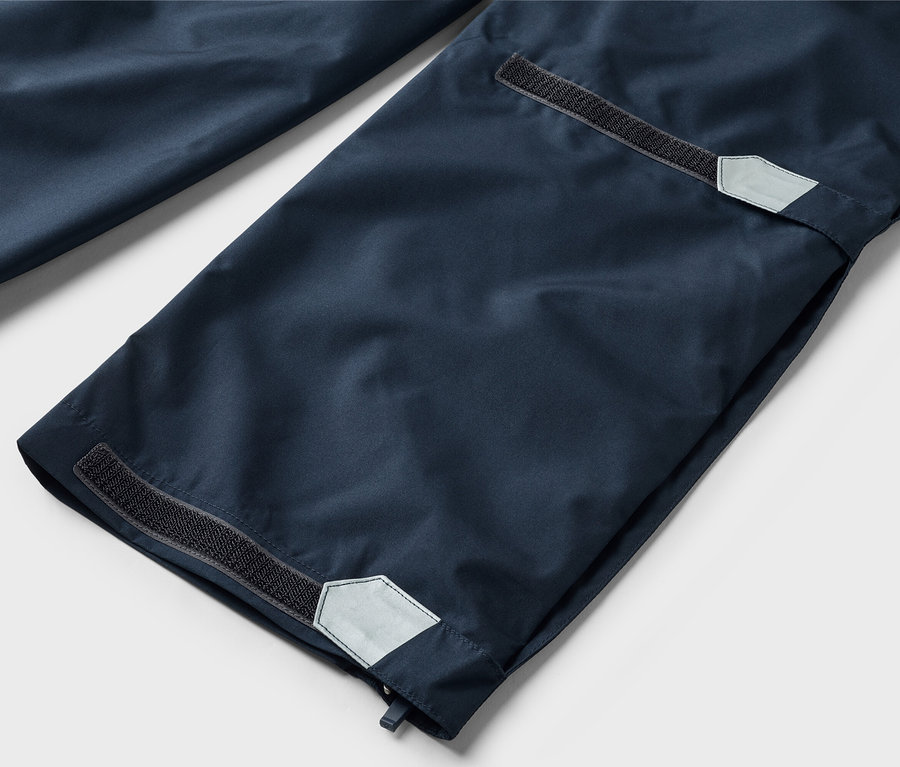 Nahaufnahme von marineblauen Hosenbeinen mit Klettverschluss und reflektierenden Details an den Säumen.