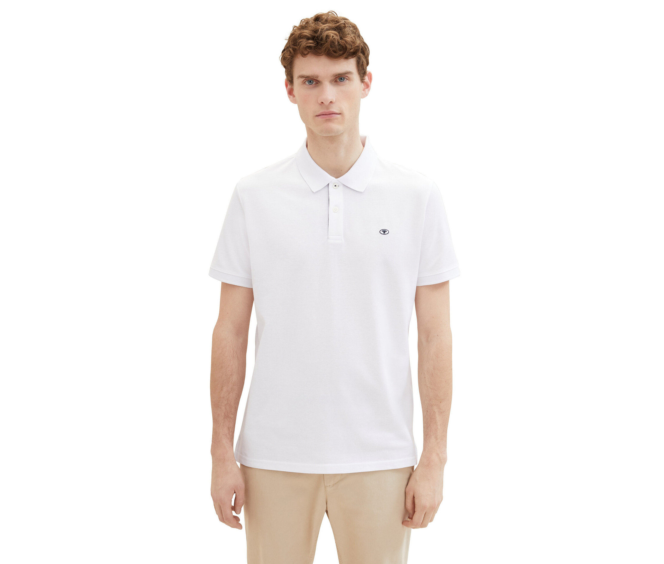 Mann mit lockigem Haar trägt ein weißes Poloshirt und eine beige Hose.