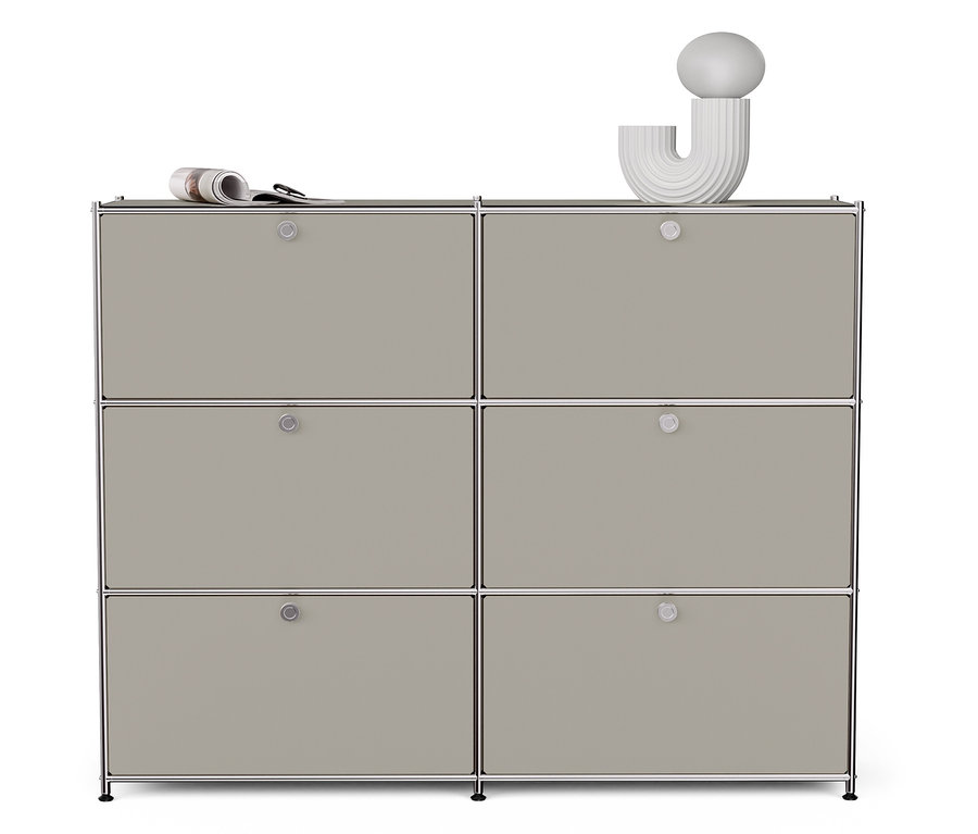 Helle graue Metall-Kommode »CN3« mit sechs Klappfächern. Auf der Kommode liegen eine Zeitung und eine weiße Dekoration.