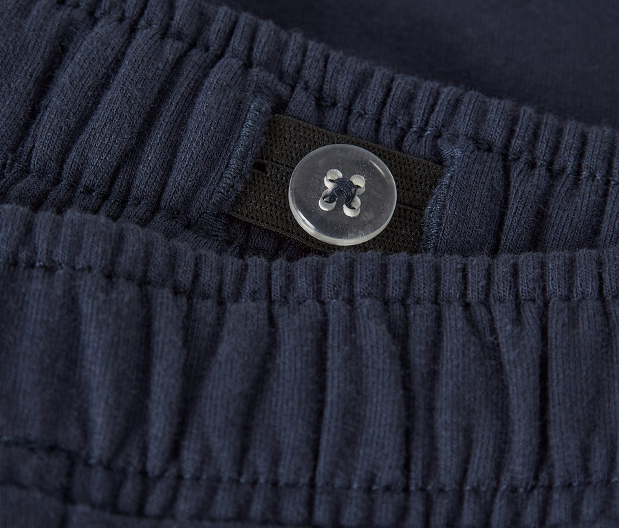 Nahaufnahme von marineblauen Stoffhosen mit elastischem Bund und verstellbarem Knopfdetail.