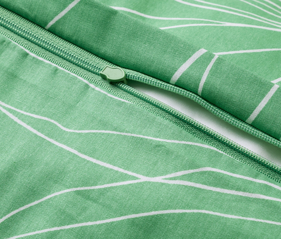 Nahaufnahme eines grünen Bettbezugs mit weißem Blumenmuster und Reißverschluss.