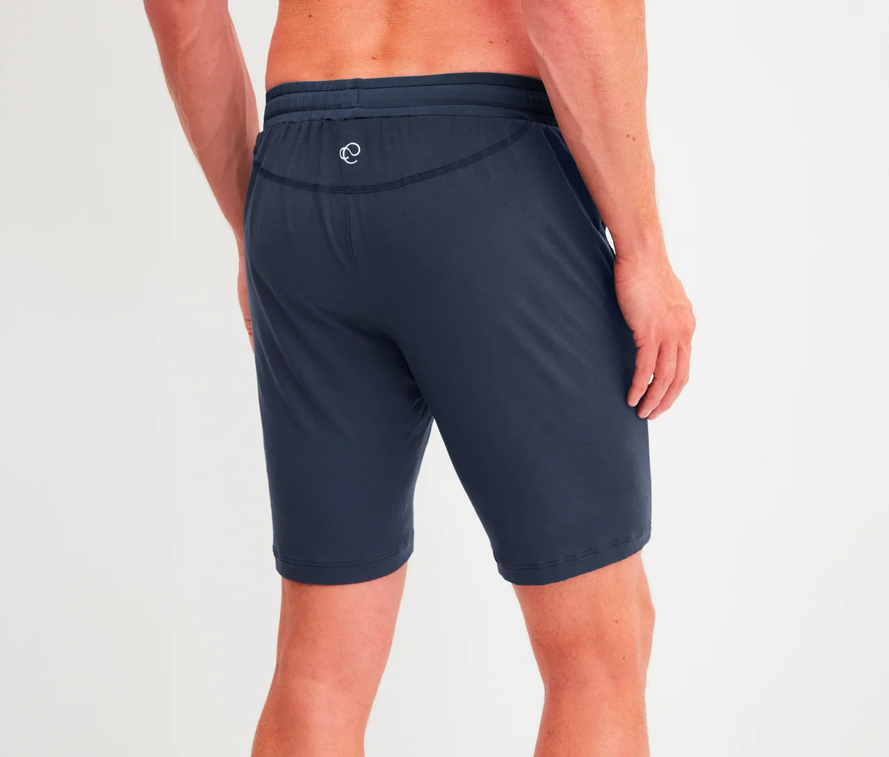 Mann von hinten, trägt dunkelblaue Shorts mit Kordelzug und weißem Logo am Gesäß.