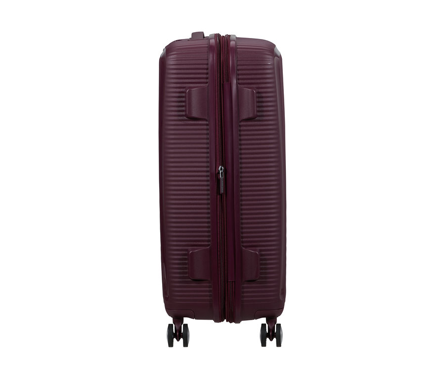 Mittelgroßer, wildkirschfarbener American Tourister Soundbox Spinner Hartschalen-Koffer, aufrecht stehend, mit gerippter Textur, zentralem Reißverschluss und vier Rollen.