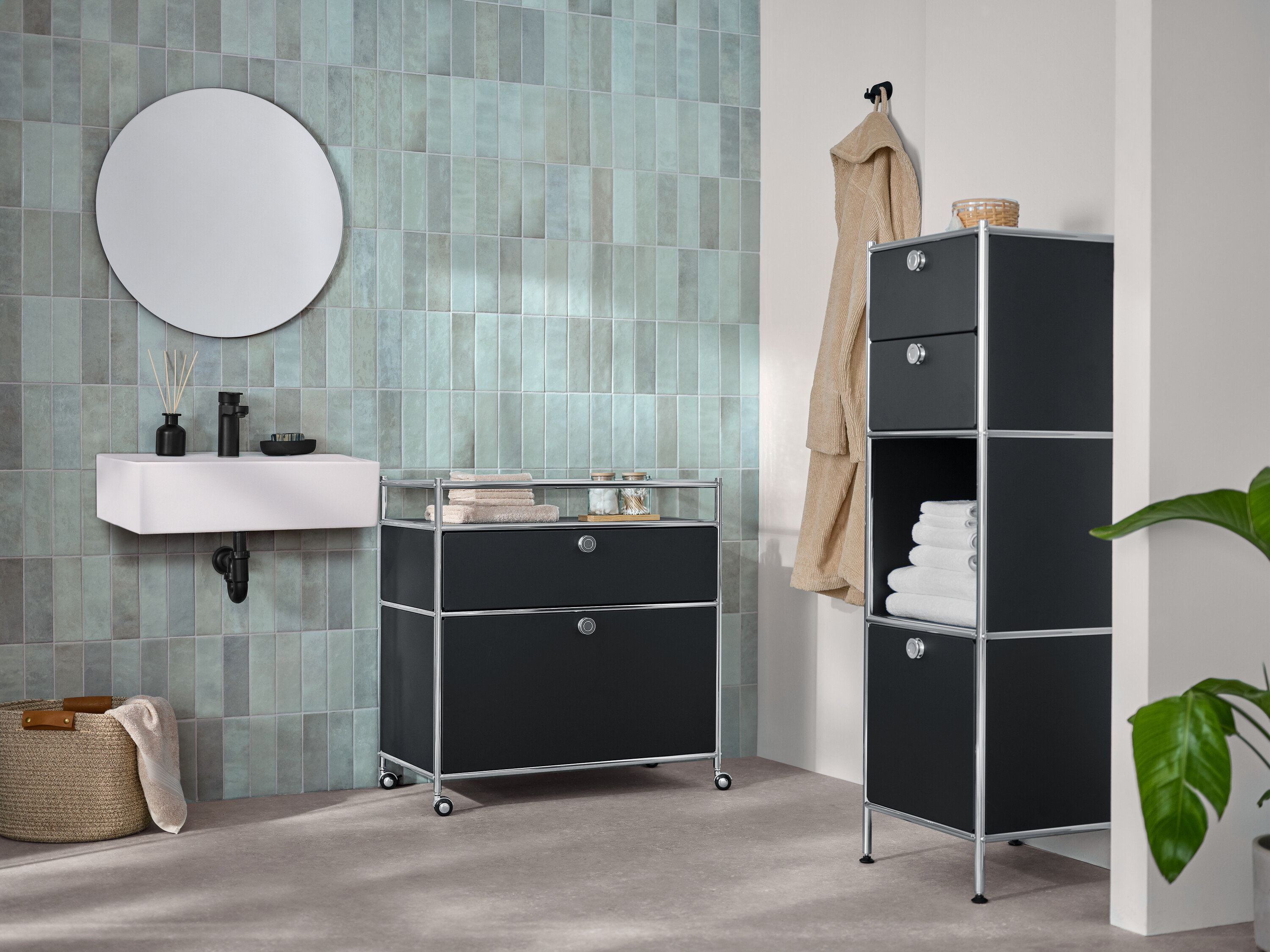 Im Badezimmer stehen eine schmale Kommode Metall »CN3« mit zwei Schubladen und 1 Klappenfach und eine Kommode Metall »CN3« mit 1 Schublade, 1 Klappenfach und Umrandung, sowie ein runder Spiegel »Ameca«.