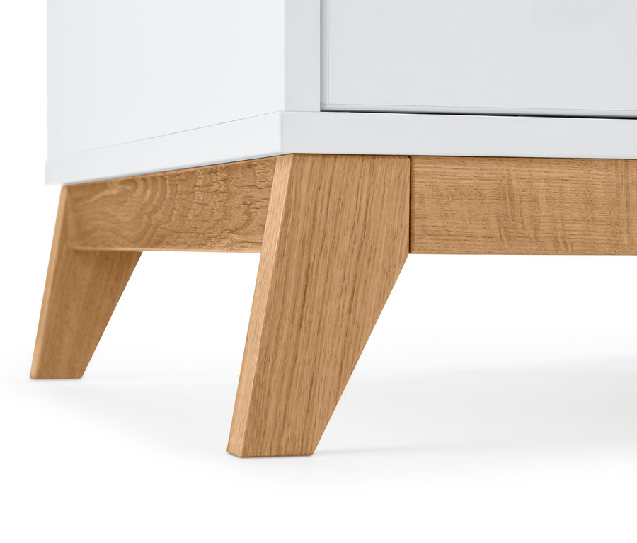 Detailansicht vom unteren Teil eines weißen Kleiderschranks mit Holzfüßen.