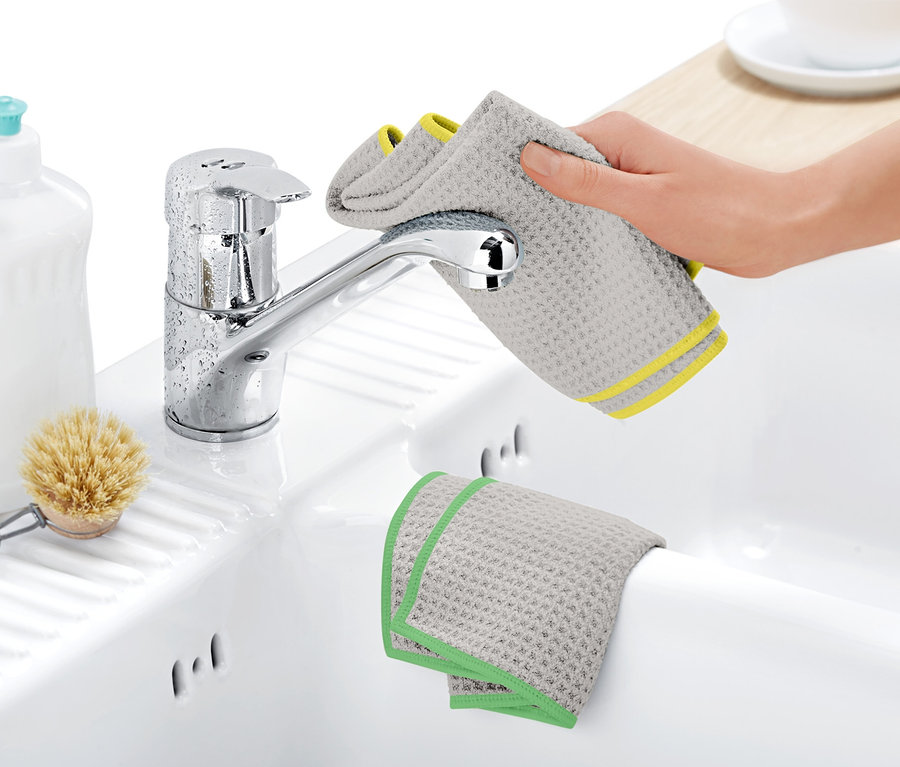 Eine Hand wischt einen Wasserhahn mit einem grauen 2 Trockentücher trocken.