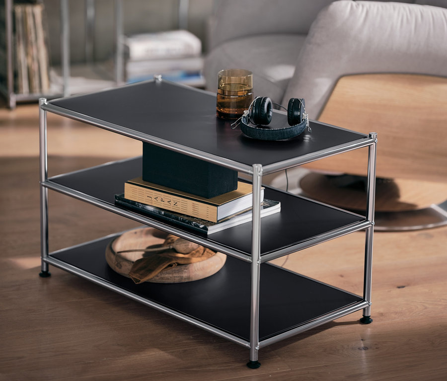 Schwarzer Couchtisch Metall »CN3« mit Glas und Kopfhörern auf der obersten Ablage.