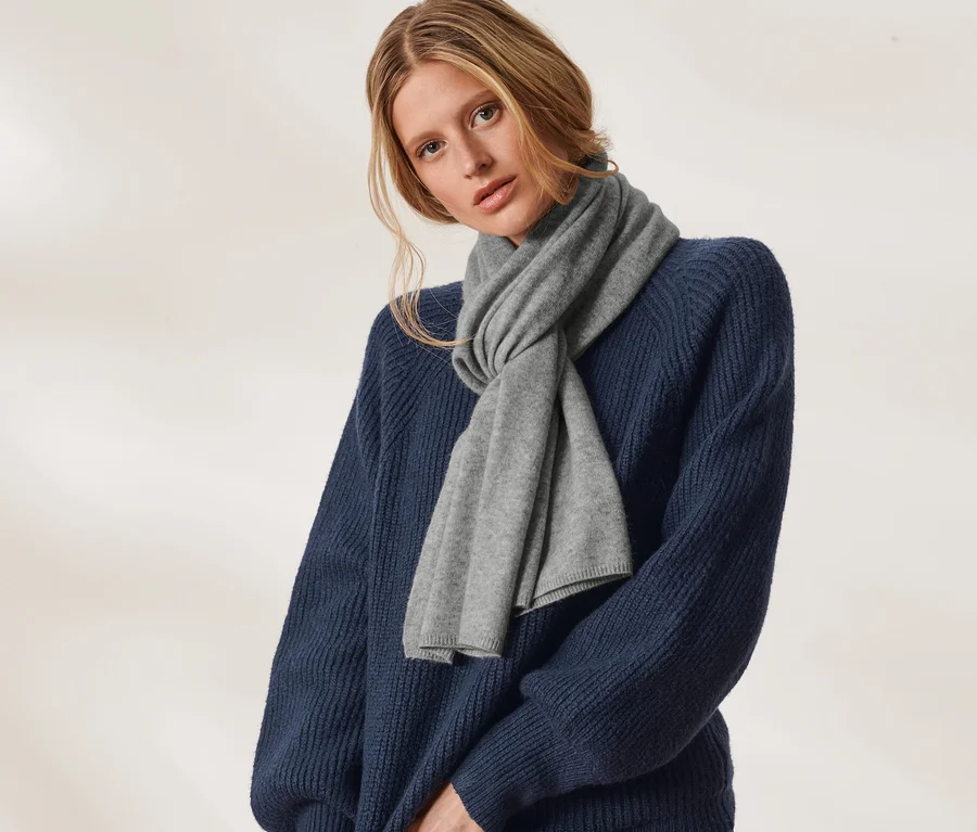 Frau posiert in blauem Pullover mit Cashmere-Strickschal.