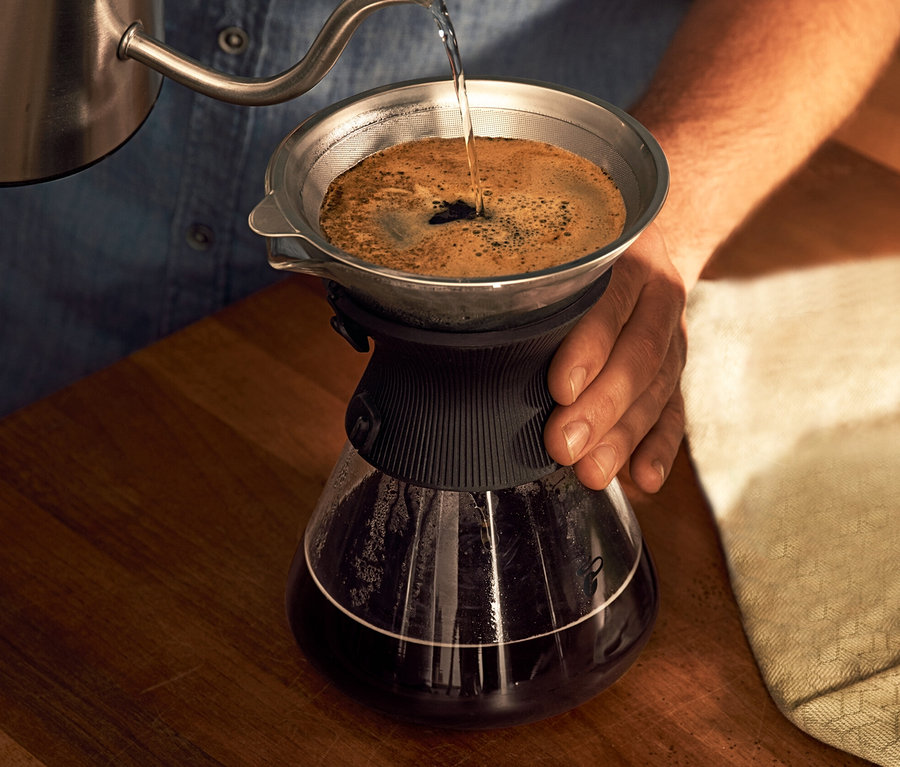 Mann gießt Wasser in eine BEEM Pour Over, 0,75 l Glaskaraffe mit Kaffeefilter.
