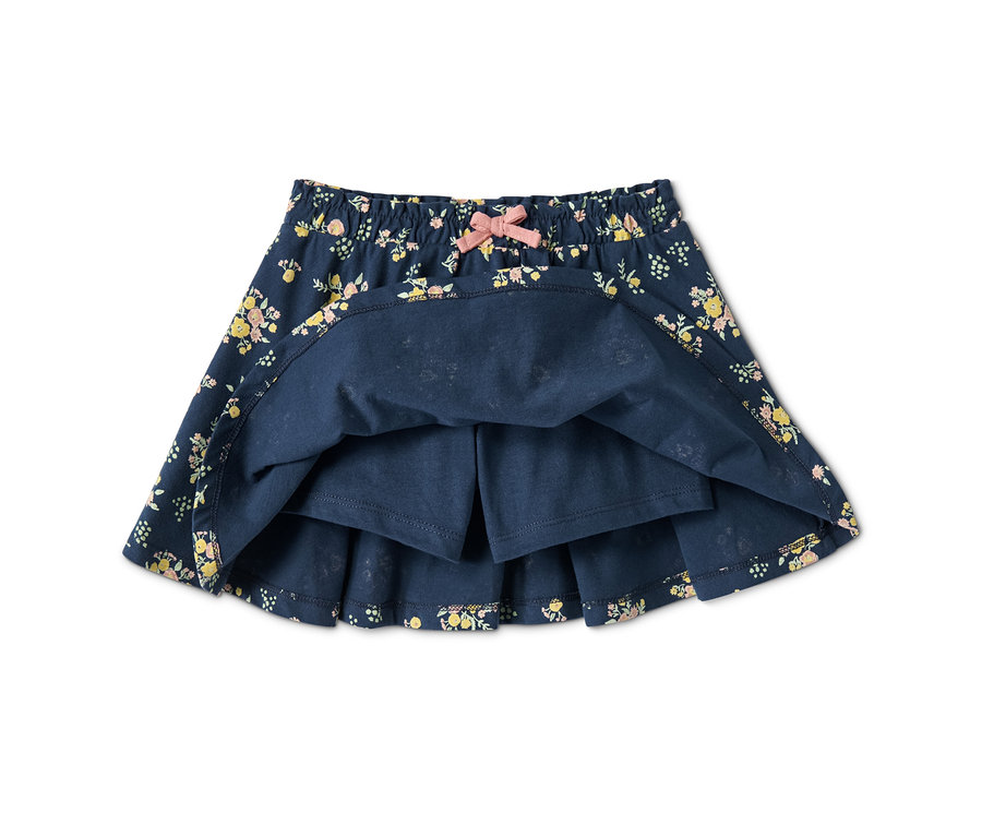 Detailansicht eines Jerseyrocks mit Hose mit Blumenmuster und rosa Schleife.