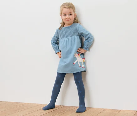 Mädchen posiert in blauem Einhornkleid und 5 Baumwoll-Strumpfhosen mit Sternen.