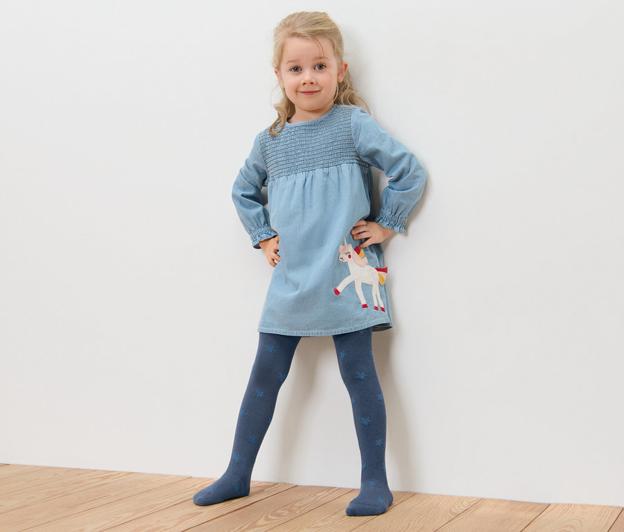 Mädchen posiert in blauem Einhornkleid und 5 Baumwoll-Strumpfhosen mit Sternen.