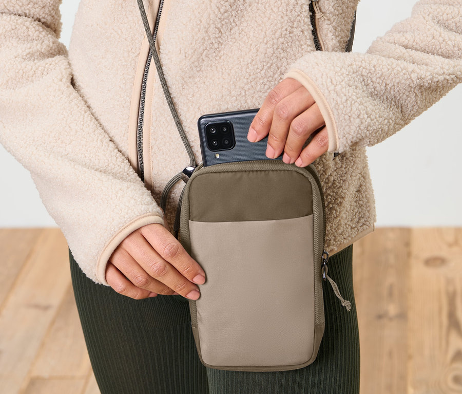 Frau legt Handy in eine taupefarbene Anti-Frost-Handytasche.