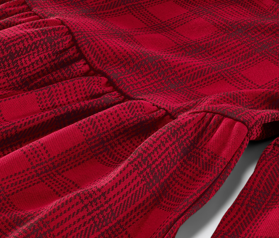 Detailaufnahme eines Kinder-Jersey-Kleids mit rot kariertem Muster.