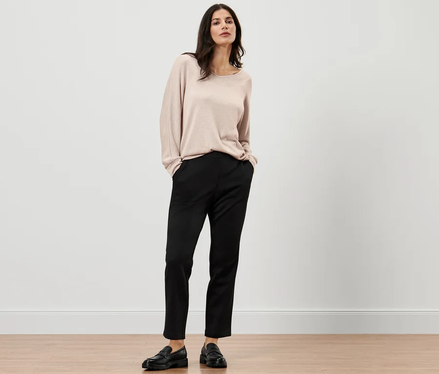 Frau posiert in schwarzen Joggpants und Pullover.