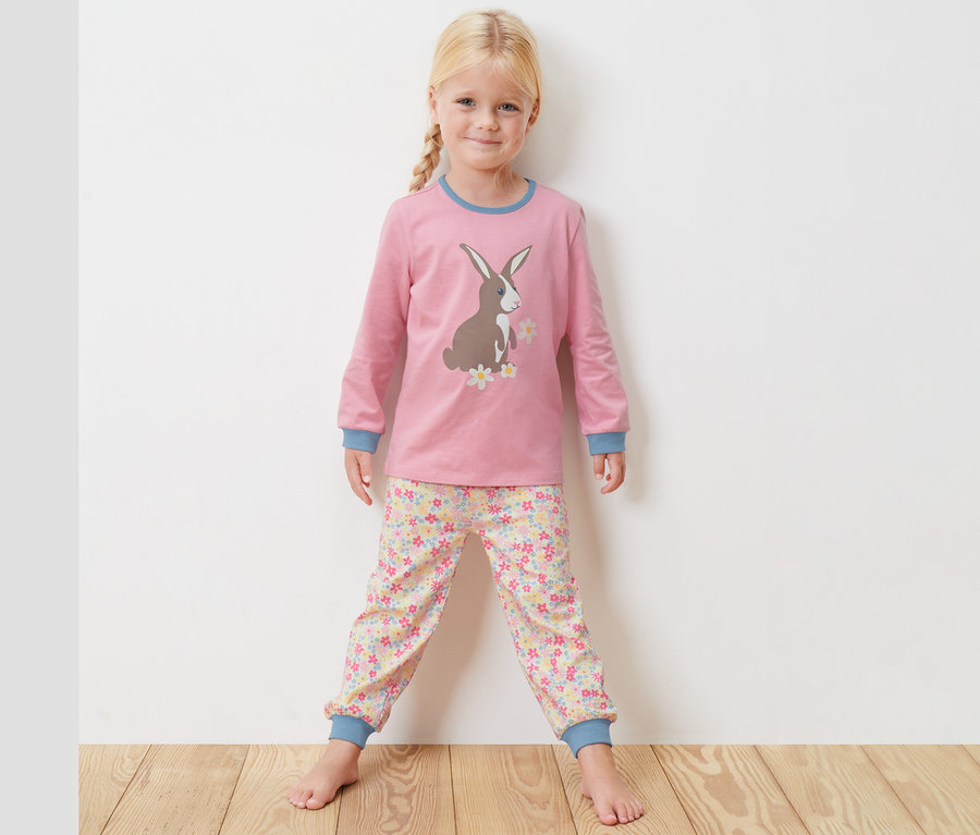 Mädchen steht und trägt einen rosa Kleinkind-Pyjama.