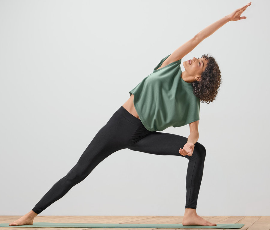 Frau macht Yogaübung und trägt dabei eine Sporthose.