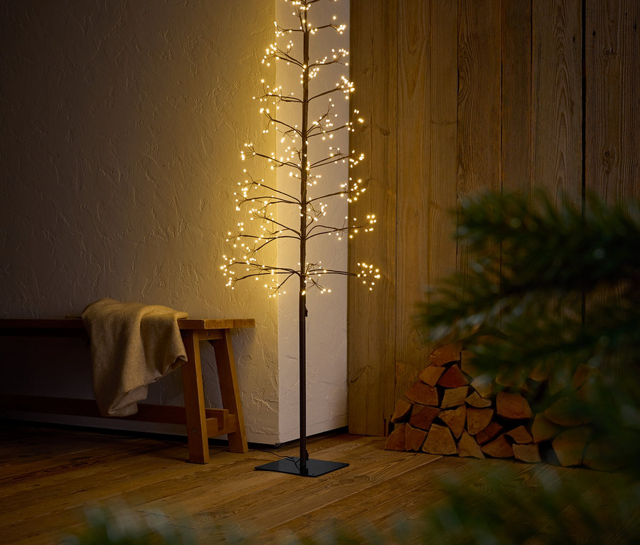 Dekorativer Baum mit Ästen und LED-Leuchten steht in einem Innenraum.