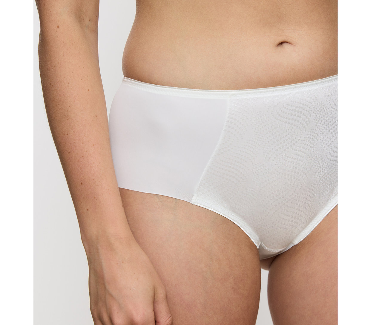 Nahaufnahme einer Person, die einen vanillefarbenen Triumph Essential Minimizer Hipster X Slip trägt. Der Slip hat ein strukturiertes Wellenmuster auf der Vorderseite.