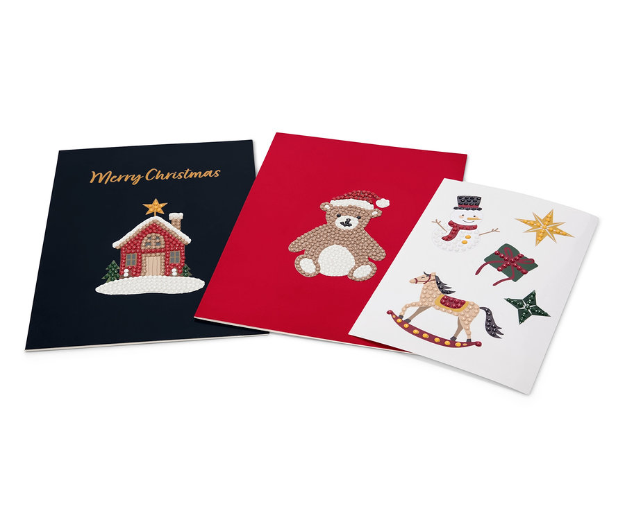 Drei Weihnachtskarten: marineblau mit Haus und "Merry Christmas", rot mit Teddybär und weiß mit Schaukelpferd, Schneemann, Geschenk und Sternen.