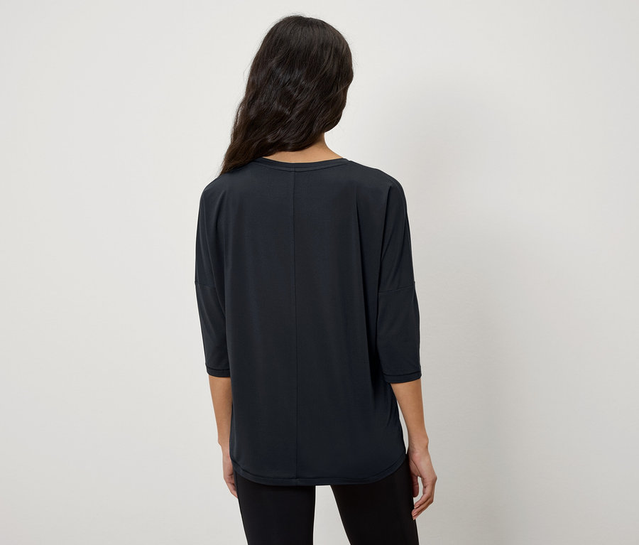 Frau mit dem Rücken zur Kamera trägt ein schwarzes T-Shirt mit Dreiviertelärmeln.