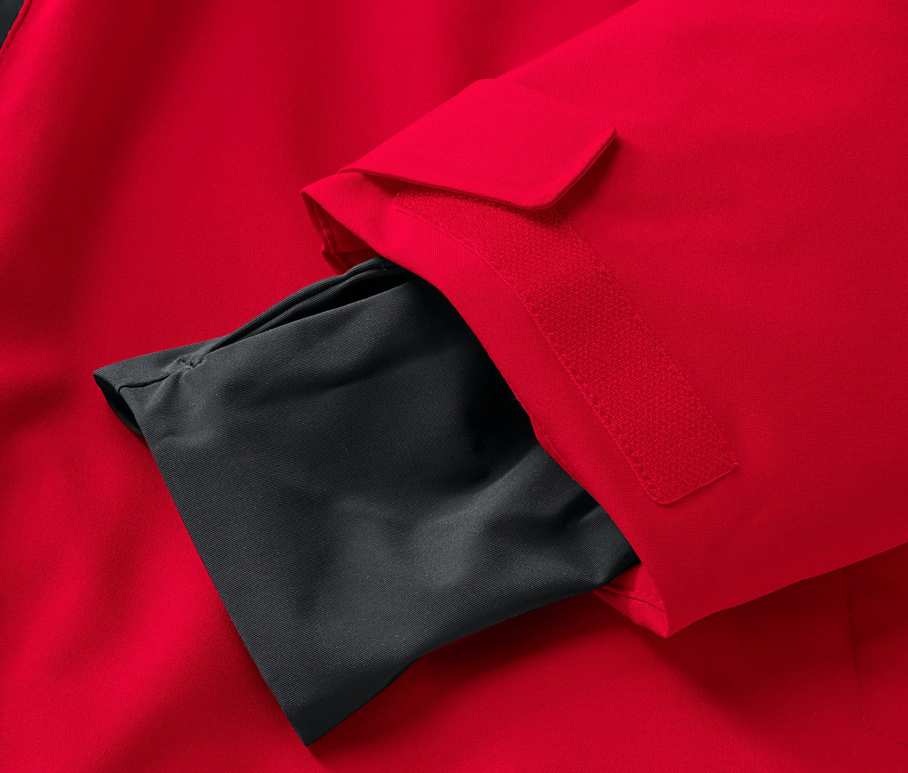 Detail einer roten Jacke mit einer schwarzen Innentasche am Ärmel.