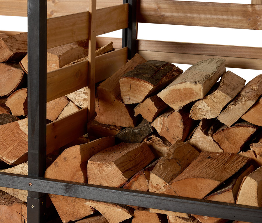 Holz gelagert in einem Kaminholzunterstand mit Rückwand.
