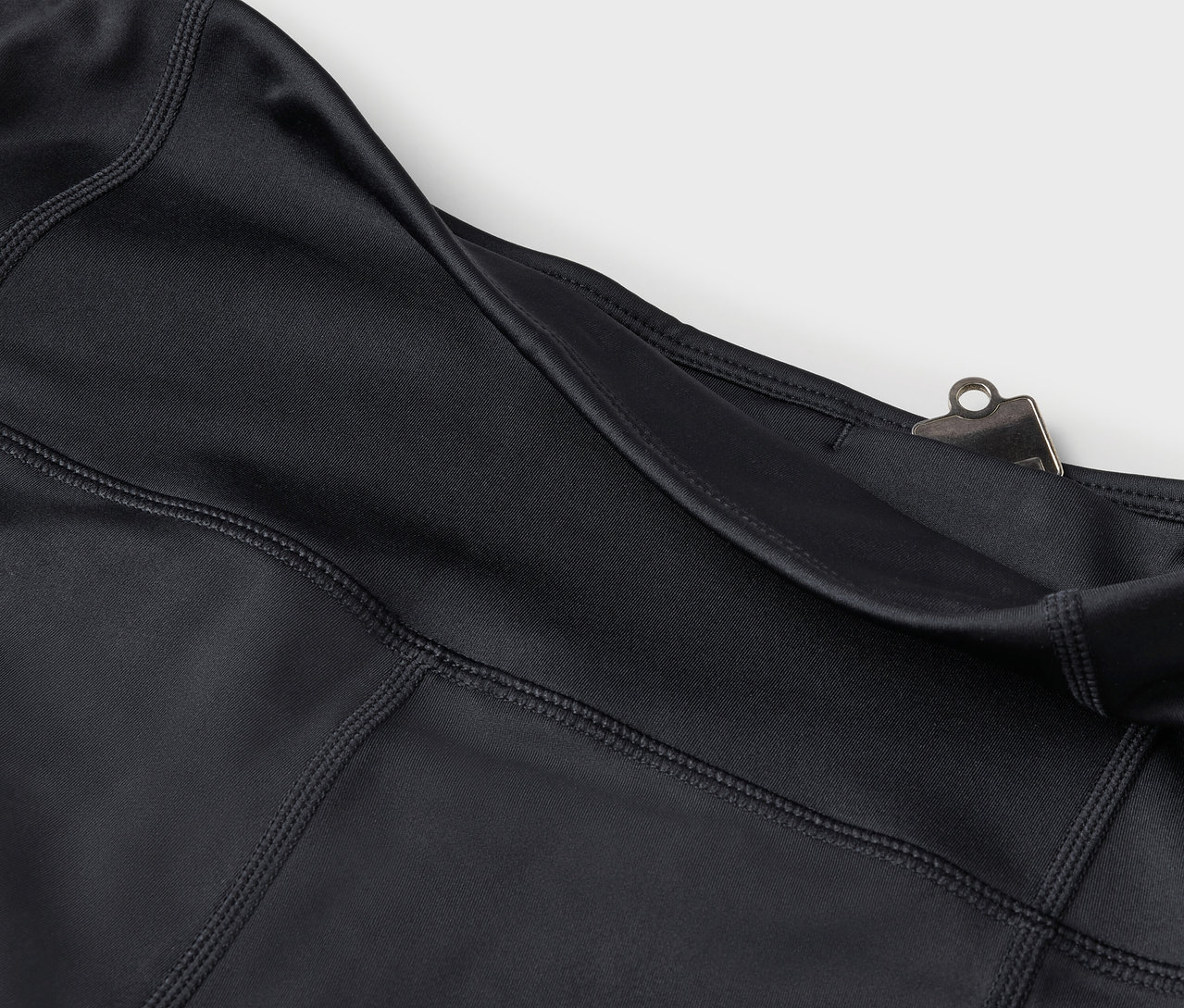 Detailaufnahme von schwarzen Leggings mit Tasche und silbernem Clip.