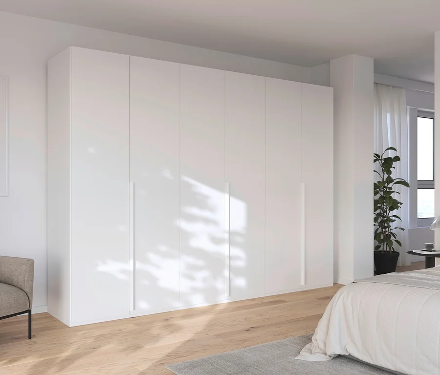 Innenaufnahme eines Schlafzimmers mit einem großen weißen Schrank, einem Bett und einem Sessel.