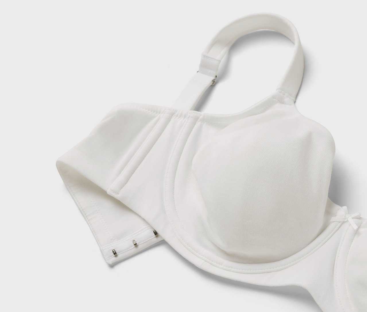 Detailaufnahme eines weißen BHs mit verstellbaren Trägern und Hakenverschluss.