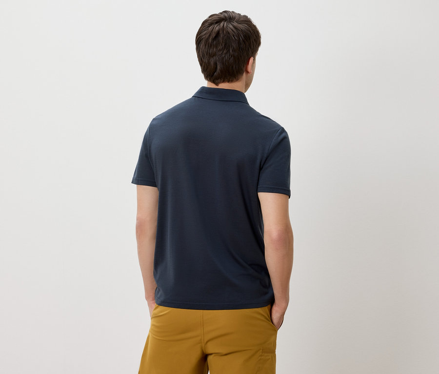 Mann von hinten in marineblauem Poloshirt und goldgelben Shorts.